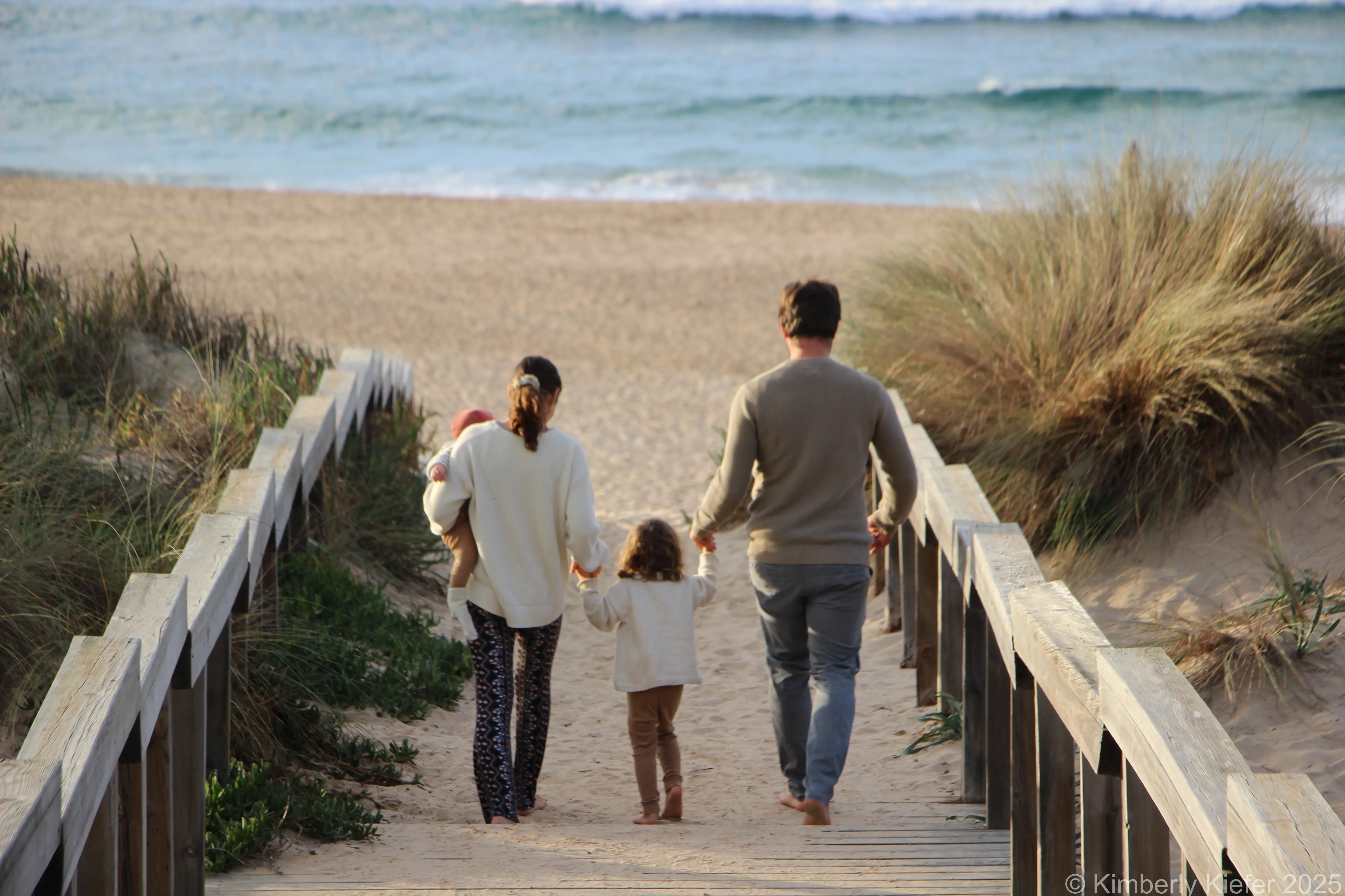Kimy und Steven mit ihren Kindern am Strand auf einer Treppe